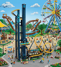 A colorful assembled toy amusement park scene with a tall blue roller coaster tower, yellow looping track, ferris wheel, carousel, rides, stalls, and small minifigures under a blue sky with clouds.