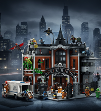 A detailed LEGO-style asylum building set with multiple minifigures, vehicles, and themed accessories on a plain white background. The central structure is a gray and red asylum building with a black arched entrance reading 'Asylum' and 'Crimen', surrounded by Batman, Robin, and other superhero minifigures.