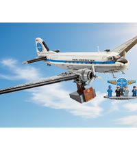 A building-block model of a Pan American passenger airplane on a display stand, shown with small minifigures and a small sign on a white background.