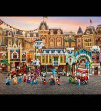 A set of three assembled building block city scenes with minifigures, shown on a plain white background. The buildings resemble a vintage town square or fairground, with storefronts, a red firecar, and multiple small character figures standing in front.