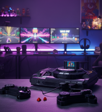 Sega Mega Drive console set with two black controllers, a small red accessory piece, a curved black strap with red buttons, a black power adapter, and a black cover on a plain white background.