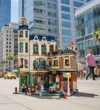 A detailed LEGO city building set featuring a multi-story apartment building with minifigures, animals, and small street details, isolated on a white background.