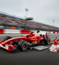 A red Ferrari-themed building block model of an F1 race car on a display stand, shown with a small minifigure and trophy on a white background.