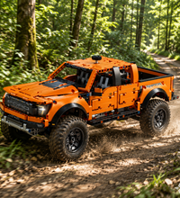 An orange and black brick-built toy pickup truck, resembling a Ford Raptor, shown from a three-quarters angle on a solid white background.
