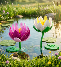 Two building block flower models on clear cylindrical bases against a white background. One flower is magenta with a yellow center and pink lower petal, and the other is white with yellow petals and green leaves and stem.