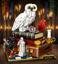 Harry Potter Hogwarts building block set featuring a large white owl, stacked books, a red crystal ball, candles, a chest, and small character figures on a checkered base, photographed on a white background.
