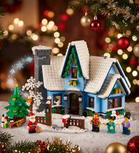 A LEGO City Fairbuilder winter village house set with snow-covered roofs, blue walls, a gray chimney, a small tree, fence, slide, and multiple minifigures on a white background.