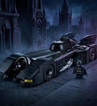Batman Batmobile set in black with silver and gray mechanical details, shown alongside a small Batman minifigure on a white background.