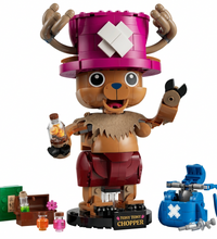 A toy building-block figure of Tony Tony Chopper from One Piece, shown standing on a black base with accessories including a blue pouch, bottles, and a small crate, all on a plain white background.